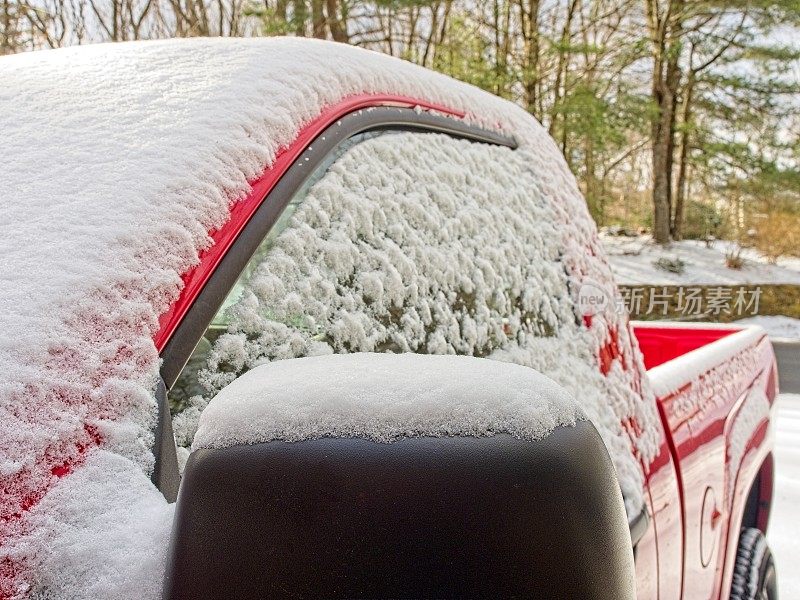 一辆红色卡车的挡风玻璃、窗户和侧视镜上覆盖着一层雪