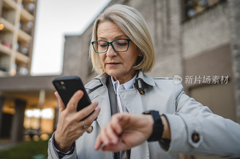 一名女子成熟女站在城市户外使用智能手表