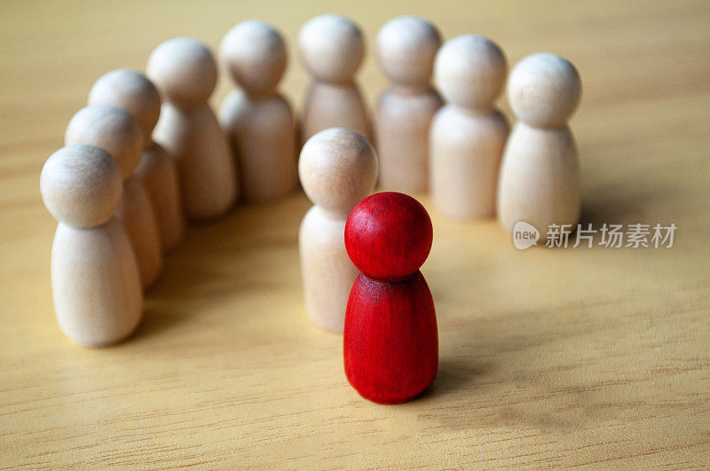 红色的木制娃娃周围的其他娃娃。代表领导或骚扰。