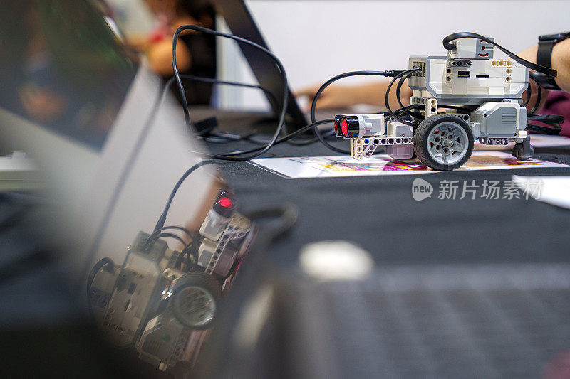 这张特写展示了一名学生勤奋地在DIY机器人汽车上工作，捕捉到了编码、技术、机器人和科学的本质。
