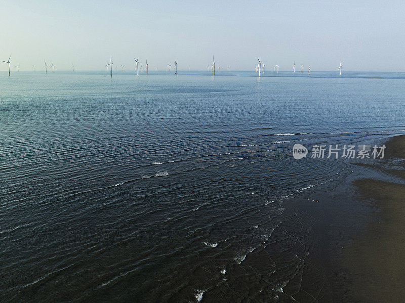 海上风力发电装置雄伟地矗立在海上，一排排的涡轮机利用风力产生可再生能源。