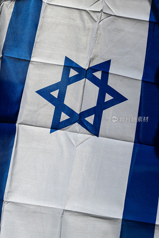 以色列国旗中央的一颗蓝色犹太星，以一定角度悬挂在建筑物的一侧。
