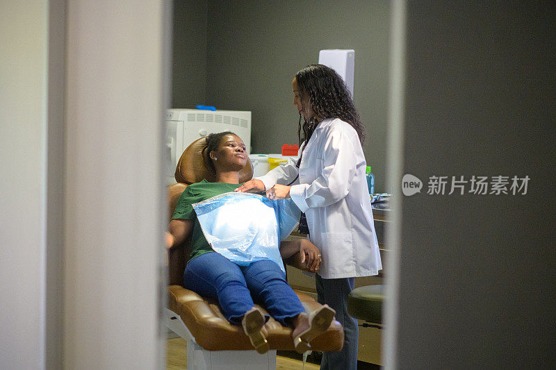 女病人坐在牙医座位上准备接受检查