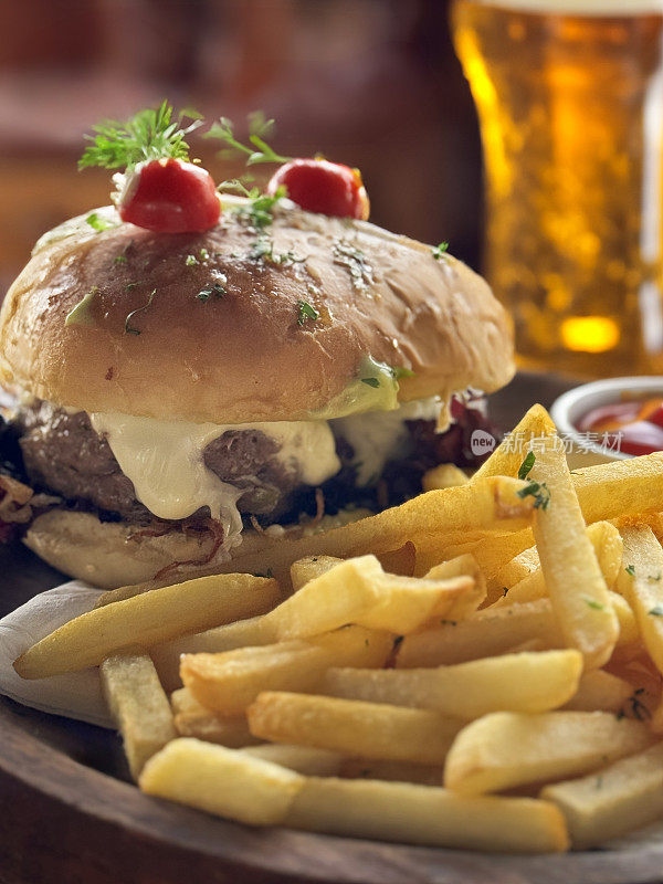 在木盘无籽汉堡面包芝士汉堡的特写图像与一堆脆炸薯条，番茄酱，一品脱啤酒，餐厅设置背景，重点在前景