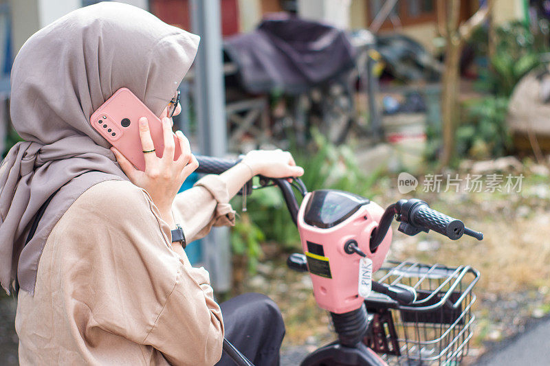 年轻的伊斯兰妇女在居民区骑电动自行车