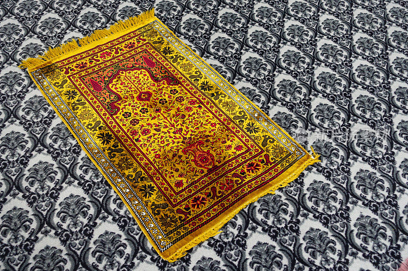 在清真寺里的祈祷毯上进行祈祷，黄色的祈祷毯，伊斯兰教和祈祷毯，