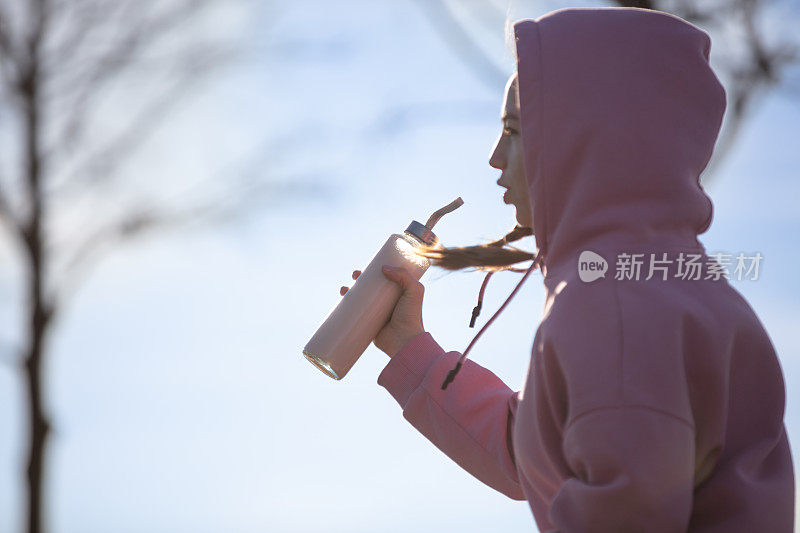 年轻女子在公园慢跑时补水。