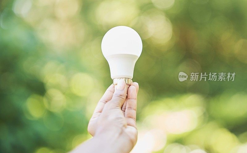 户外、可再生能源和手用灯泡，为绿色电力发展带来积极影响。拿着灯泡，环保和自然的碳足迹，改变和可持续发展的想法