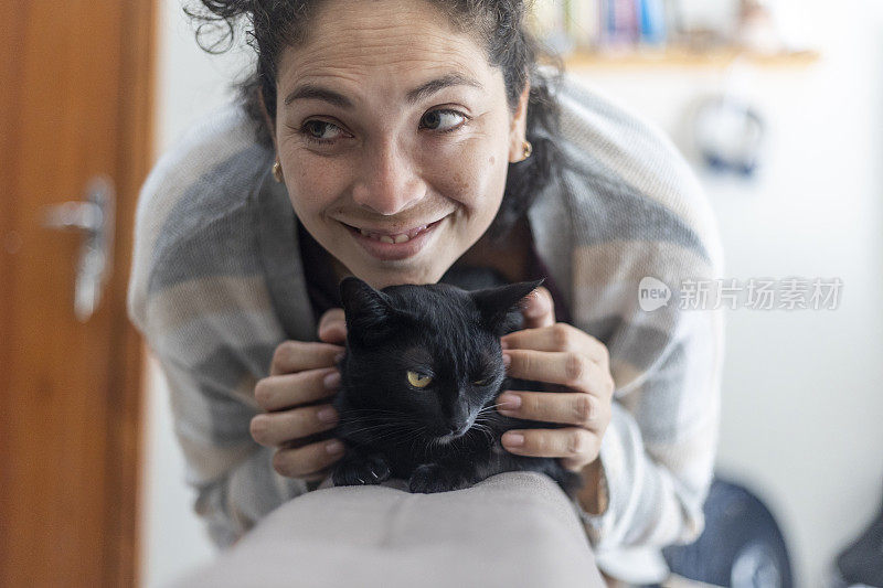 拉丁妇女在家里抚摸黑色宠物猫