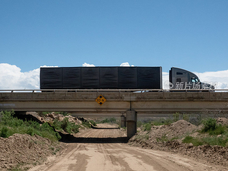 半挂车在沙漠低空立交桥上穿过一条土路。犹他州70号州际公路。