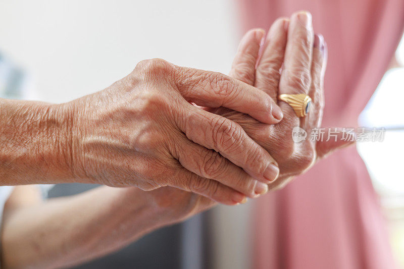 一名亚洲老年妇女在家按摩手掌的剪短照片，明显患有关节炎