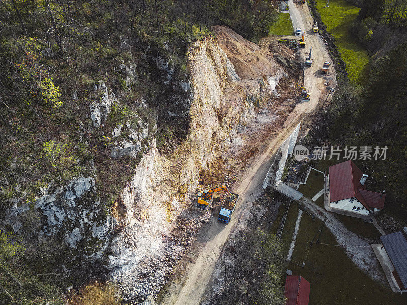 鸟瞰图，在美丽的绿色自然中间的小采石场，在采石场工作的装载机和自卸卡车的俯视图
