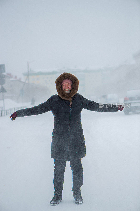 冬天来了，大暴雪来了。道路上有大雪，能见度低。妇女在危险的天气里缓慢而艰难地行走。大自然的大灾难。城市人的生活理念是暴风雪。