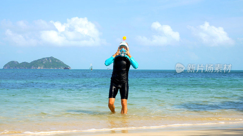 一名男子戴着全脸浮潜面罩，从热带海洋中走到沙滩上，体现了浮潜的刺激。视频理想的浮潜推广，捕捉热带浮潜冒险的精髓。