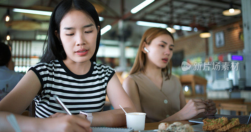 两名年轻女子在一家咖啡店闲坐着工作。