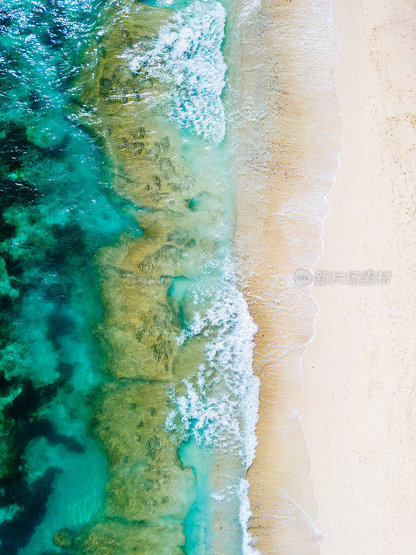 绿松石般的海浪与沙滩“梅拉斯蒂”海滩相遇:鸟瞰清澈的海水和白色的泡沫。