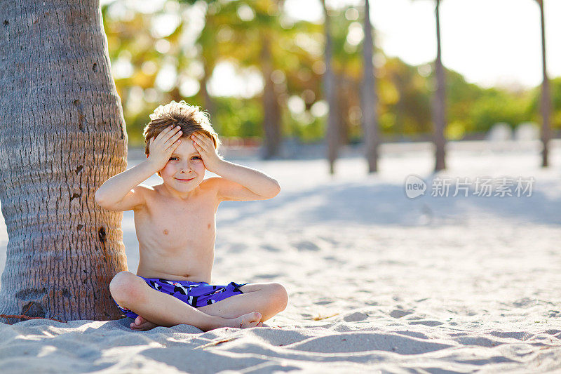 金发可爱漂亮的小男孩在迈阿密海滩上玩得很开心，比斯坎湾。快乐健康可爱的孩子在海边玩沙子和奔跑。棕榈树，安全屋和白沙