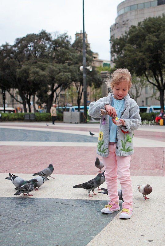 小女孩在广场上喂鸽子
