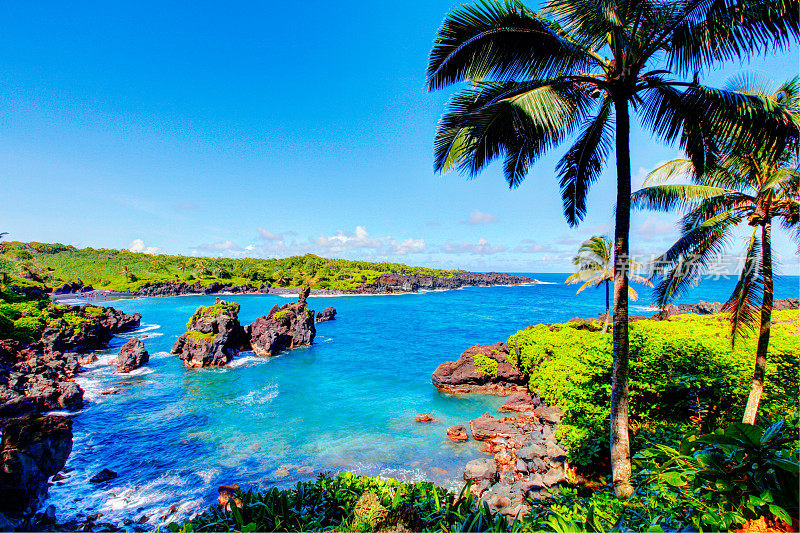 在一个阳光明媚的日子里，海浪拍打着岩石。毛伊岛