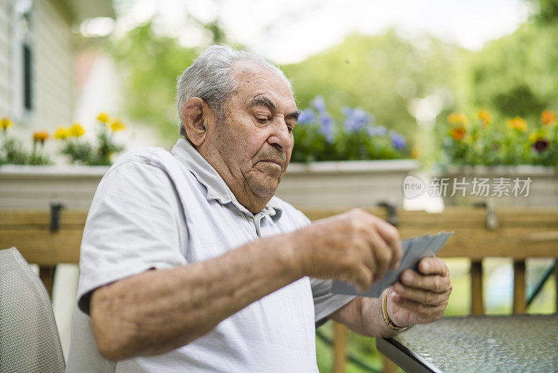 90岁高龄老人在户外门廊打牌的特写