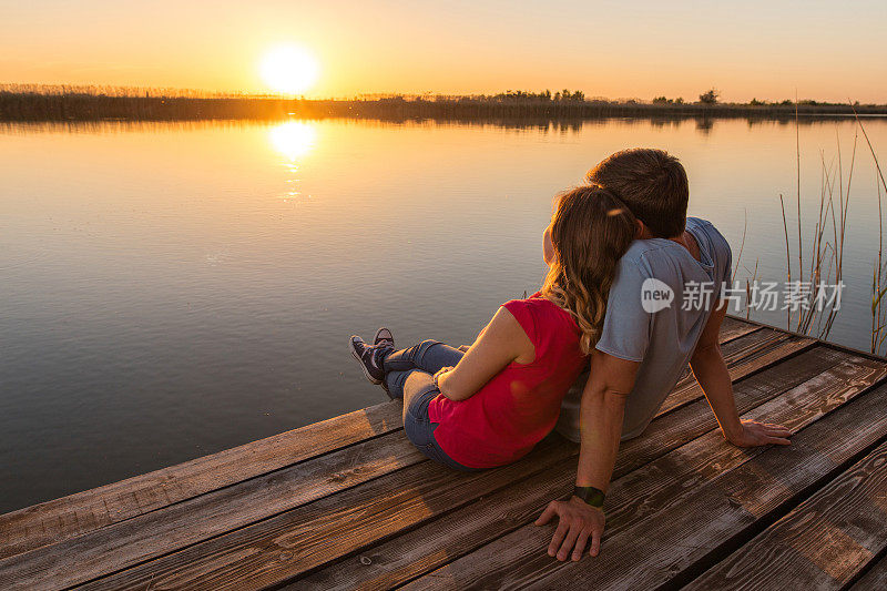 浪漫的情侣在湖边欣赏日落。
