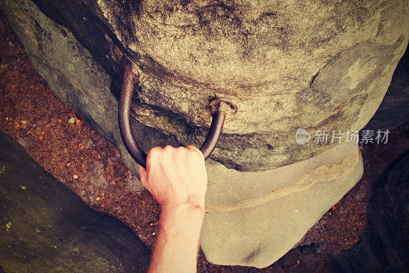 攀岩者的手放在固定在岩石上的钢把手上。
