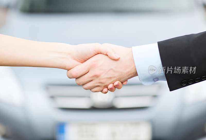 顾客和销售员在汽车上握手