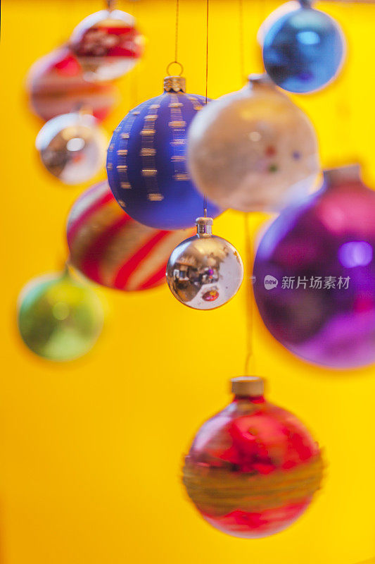 散焦圣诞装饰品挂在黄色背景前。