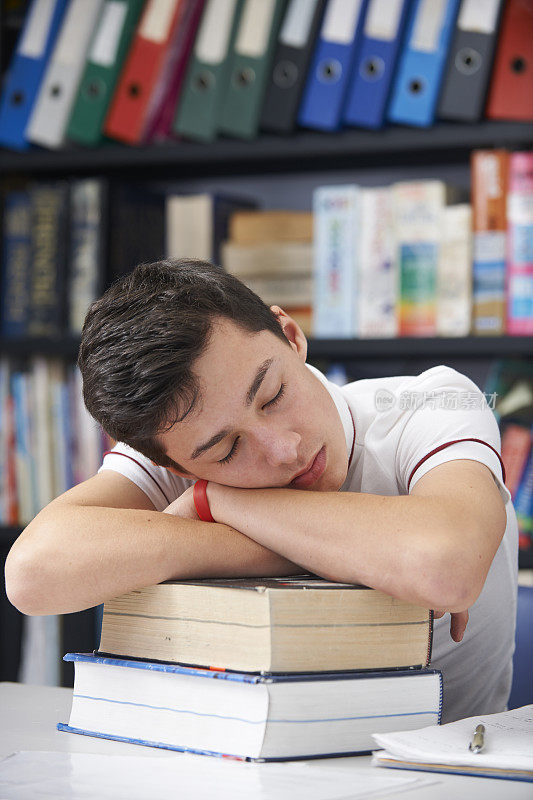 疲惫的男学生睡在图书馆