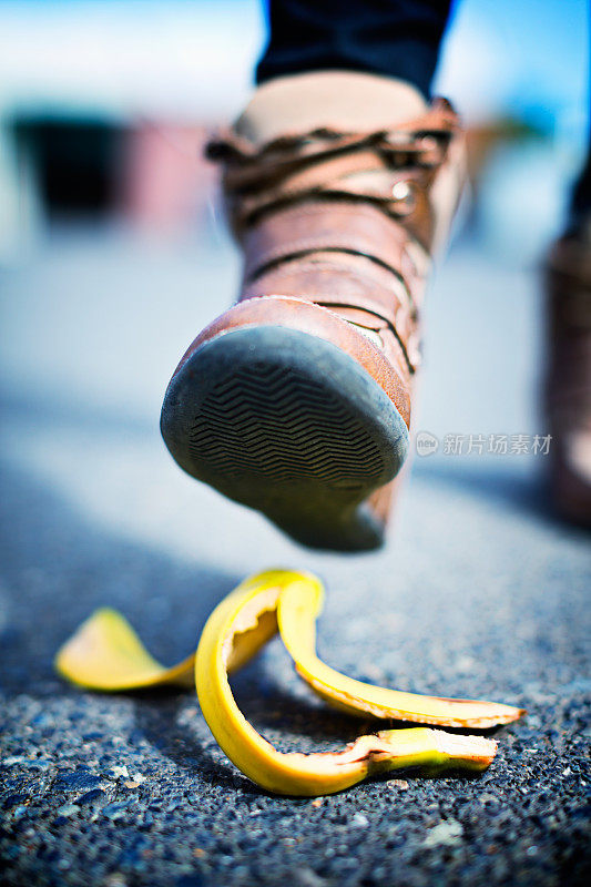 湿滑的情况!穿靴子的脚在街上接近香蕉皮