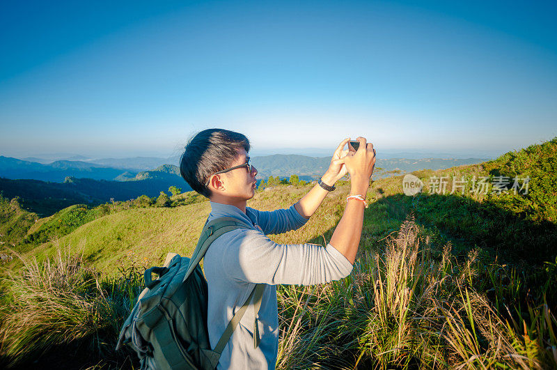 年轻的旅行者站在山上望着夕阳。