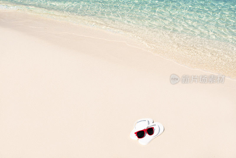 白色人字拖和太阳镜在沙滩上