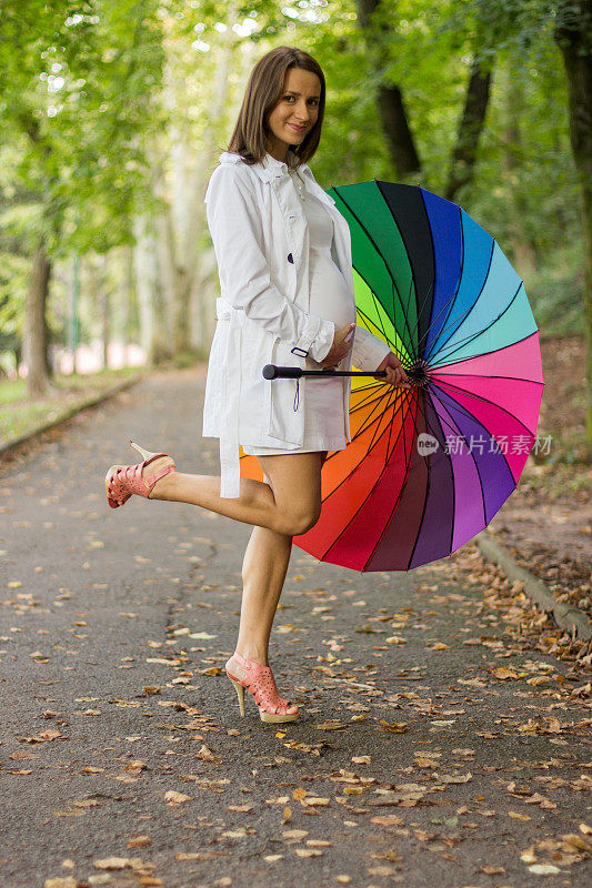 快乐孕妇撑五彩伞在雨中