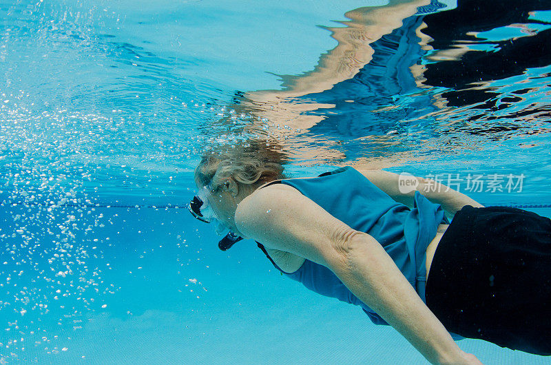 67岁的妇女戴着通气管和面罩在水下游泳
