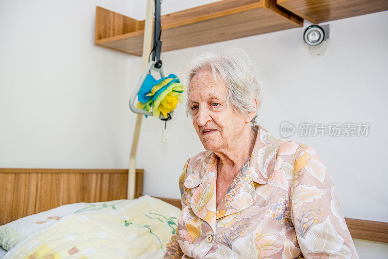老年妇女在养老院坐在床上的肖像