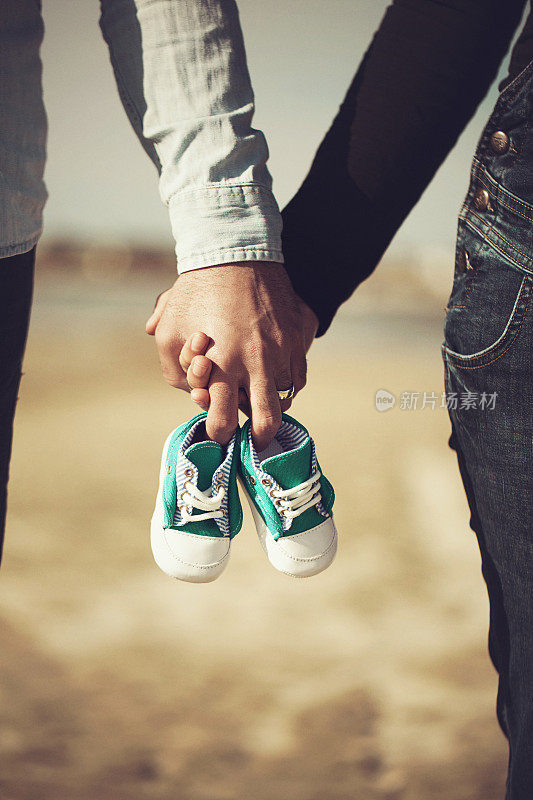 未来的父母手牵着手，穿着一双小鞋