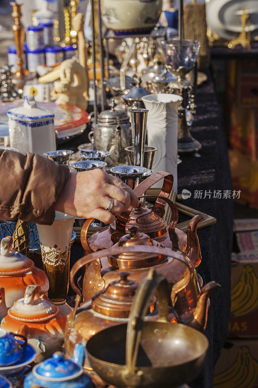 一个女人在露天市场上看精品店和古董。