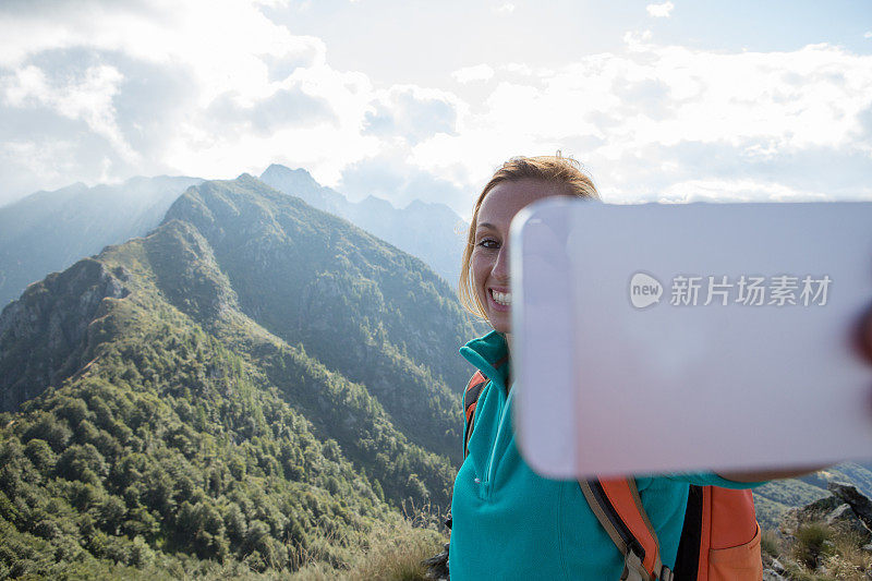 登山女性在山顶用手机自拍