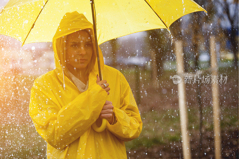 雨中穿着黄色雨衣的年轻女子