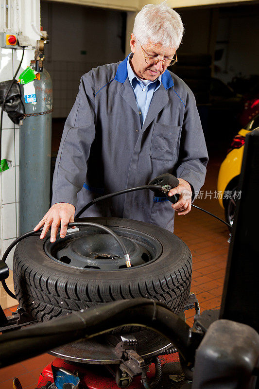 在汽车修理厂…汽车修理工正在检查轮胎气压