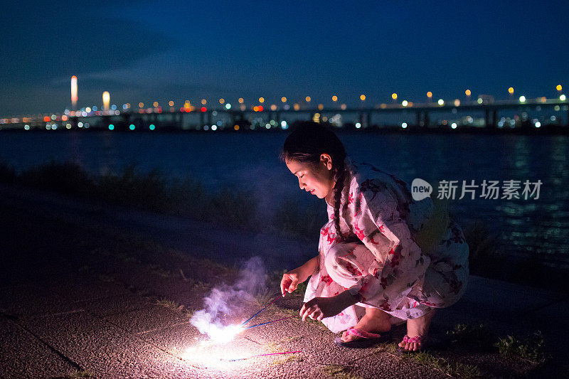 年轻的浴方女子玩火花附近的河