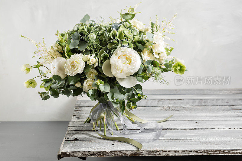 新娘的花束。新娘的。古色古香的木桌上，点缀着美丽的混合鲜花和绿叶，丝带点缀着。复古风格
