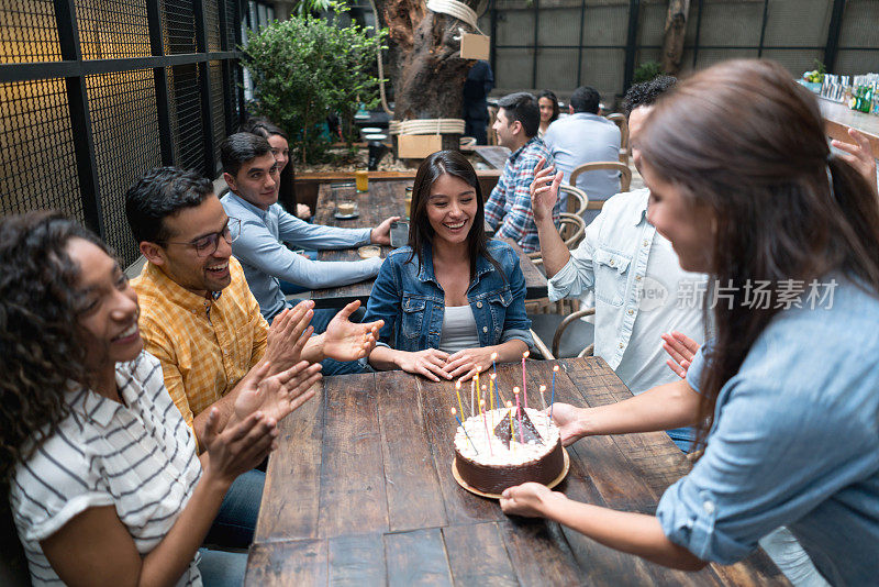 快乐的女人和一群朋友在餐厅庆祝她的生日