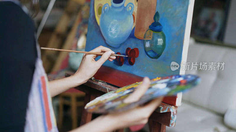特写的艺术家女人的手与画笔在帆布上画静物画在艺术工作室