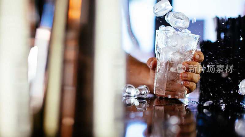 调酒师将冰块倒入玻璃杯