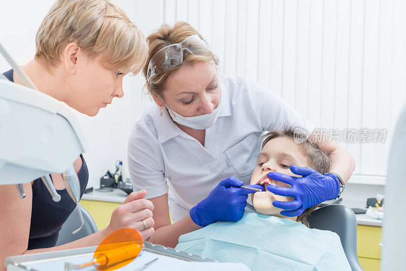 一个男孩和一个母亲正在给牙医治疗牙齿