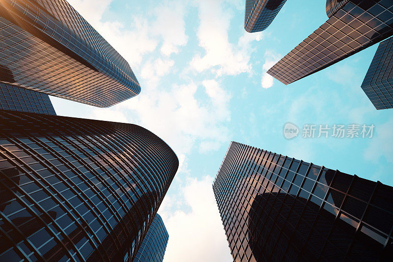 摩天大楼的低角度视图。日落时仰望摩天大楼的视角。在傍晚日落时，在商业区的现代摩天大楼的底部视图。商业理念的成功行业技术架构。