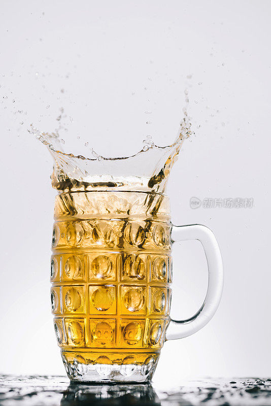 在透明的玻璃杯中洒上淡啤酒