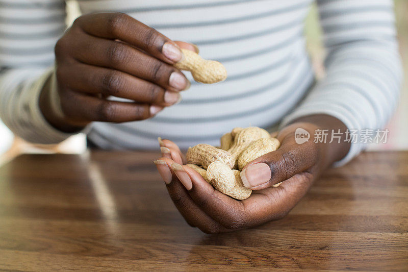 特写的十几岁的女孩与一把花生在壳