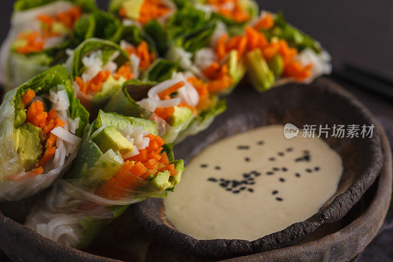 新鲜手工制作的纯素亚洲春卷，配以米粉、牛油果、胡萝卜和芝麻酱。